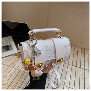 Detail of light beige baguette bag with ostrich pattern texture and cute charms