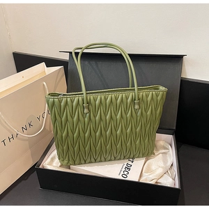 Détail du cabas vert matelassé avec texture plissée ondulée dans un coffret cadeau