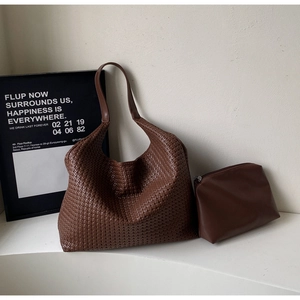 Detail of dark brown woven tote bag set featuring smooth leather zip pouch and shoulder strap