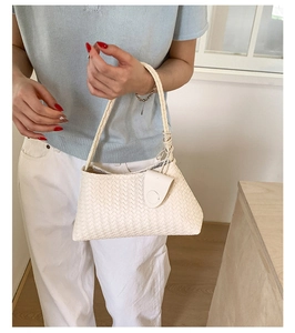 Detail of cream woven leather texture and knot handle on a minimalist hobo bag