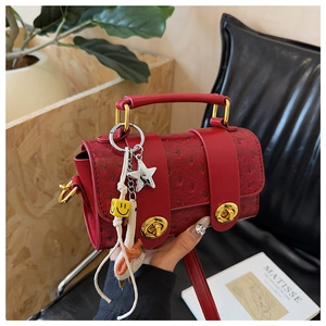 Detail of red ostrich embossed mini bag with gold twist locks and decorative charms