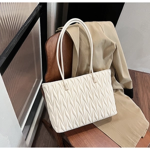 Détail du sac cabas blanc crème avec texture plissée matelassée sur une chaise en bois