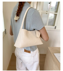 Detail of white woven leather underarm bag with square texture shown in lifestyle setting