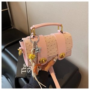 Detail of pink ostrich texture shoulder bag with gold clasp and decorative star charms