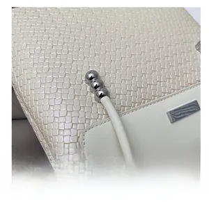 Close-up of off-white woven texture tote with silver bead charms and metal hardware