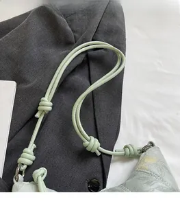 Detail of mint green shoulder bag featuring a unique knotted strap and floral pattern