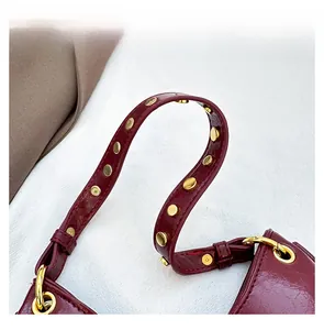 Detail view of burgundy leather handle with golden metallic rivets and precise stitching