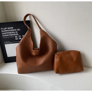 Brown woven hobo bag and matching pouch set displayed on a minimalist white stand