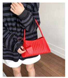 Detail of red woven leather handbag featuring intricate Intrecciato craftsmanship texture