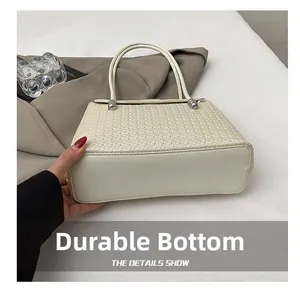 Detail showing the wear-resistant reinforced bottom of this cream woven shoulder bag