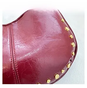 Macro shot of dark red wrinkled patent leather texture with gold stud embellishments