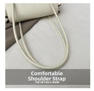 Detail shot of the comfortable leather straps with fine stitching on an off-white tote bag