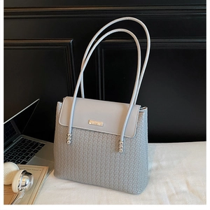 Macro view of grey woven tote bag with silver ball metal accents and square clasp flap