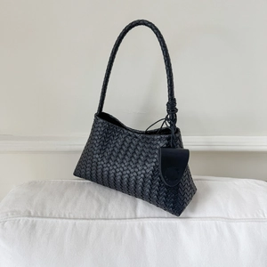 Close-up of black woven leather shoulder bag featuring intricate knot detail and mini pouch