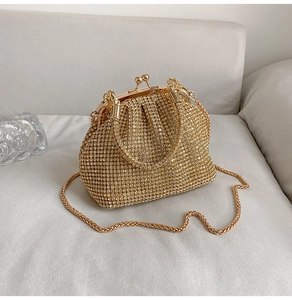 Dettaglio ravvicinato di una borsa da sera dorata con strass, chiusura vintage e catenella