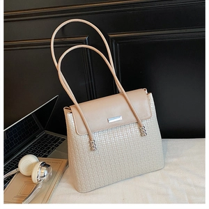 Detail of beige textured tote bag featuring sleek metal hardware and slim rope shoulder straps