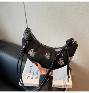 Detail of black floral fabric crescent bag featuring stylish leather knotted strap