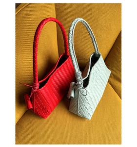 Detailed view of red and light blue woven leather handbags with knot handle on sofa