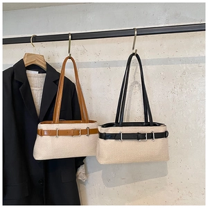 Detail of woven straw tote bags with leather belts in brown and black on a rack