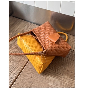 Detail of hand-woven leather textures on yellow and brown shoulder bags on wood