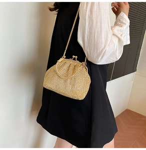 Borsa da sera dorata con strass e catena metallica indossata sulla spalla dalla modella