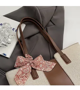 Detail of cream canvas tote bag with brown leather strap and red paisley scarf accent