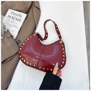 Detail of burgundy moon bag with gold studs and glossy leather in a lifestyle setting