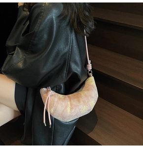 Detail of floral dumpling bag with knotted shoulder strap worn over a black leather jacket