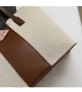 Detail of contrast stitch on beach tote bag with canvas and brown leather panels