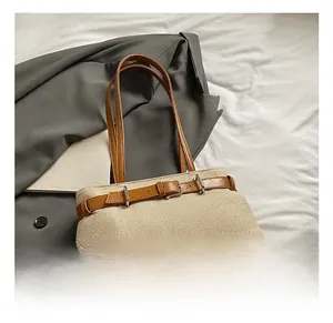 Close-up of beige woven tote bag featuring brown leather trim and silver metal buckle