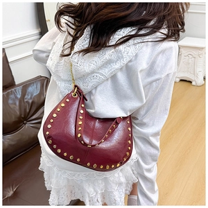 Detail view of burgundy moon bag with gold stud trim and elegant metal chain strap