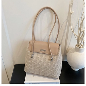 Detail of beige woven tote bag showing diamond texture and silver metal bead accents