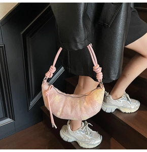 Detail of pink dumpling bag with floral jacquard texture and knotted strap design