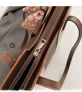 Detail of smooth metal zipper and decorative paisley silk scarf on a brown tote bag