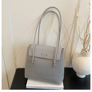 Detail of grey woven shoulder bag with metallic trim and decorative beaded strap handles