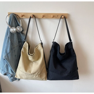 Dettaglio di borse in tela beige e nere con tracolla in pelle in un contesto minimal