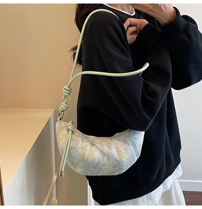 Light green floral crescent bag with knot shoulder strap worn by a female model