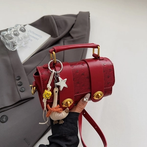 Red ostrich leather shoulder bag with gold twist locks and decorative charms for women