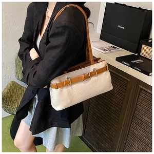 Detail of beige woven canvas shoulder bag with brown leather straps on model