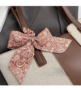 Close-up of contrast tote bag featuring brown leather trim and paisley scarf detail