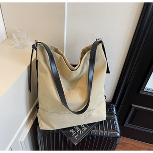 Detail of canvas tote bag with black leather straps placed on a black suitcase for travel