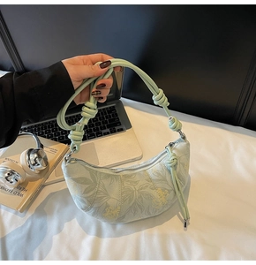 Detail of floral print dumpling bag with unique thick knotted rope handle and zipper