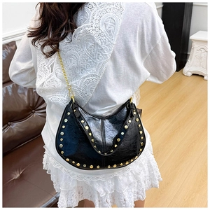 Close-up of black studded shoulder bag with golden rivets and metallic chain strap