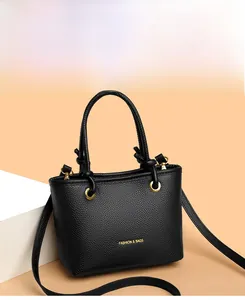 Detail of black litchi grain leather tote with gold rings and adjustable shoulder strap