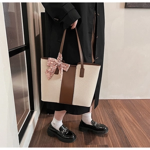 Detail of canvas tote bag with brown leather trim and decorative paisley ribbon handle