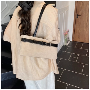 Detail of beige woven shoulder bag with black leather belt buckle on female model back