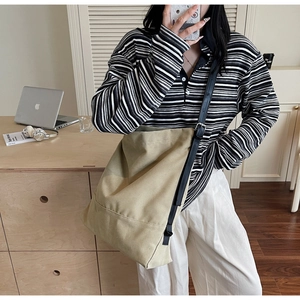 Detailansicht der khakifarbenen Canvas-Tasche mit schwarzem Lederriemen an einem Model