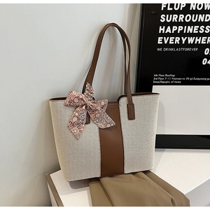 Detail of canvas tote bag with brown leather trim and decorative paisley silk scarf