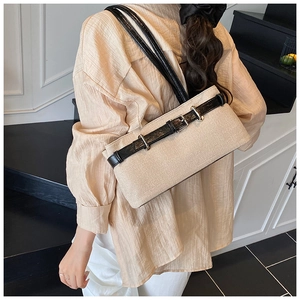 Detail of contrast canvas underarm bag with black leather strap and belt buckle decor