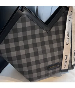 Detailansicht der schwarz-grauen Karostruktur mit Lederbesatz und Logo-Plakette